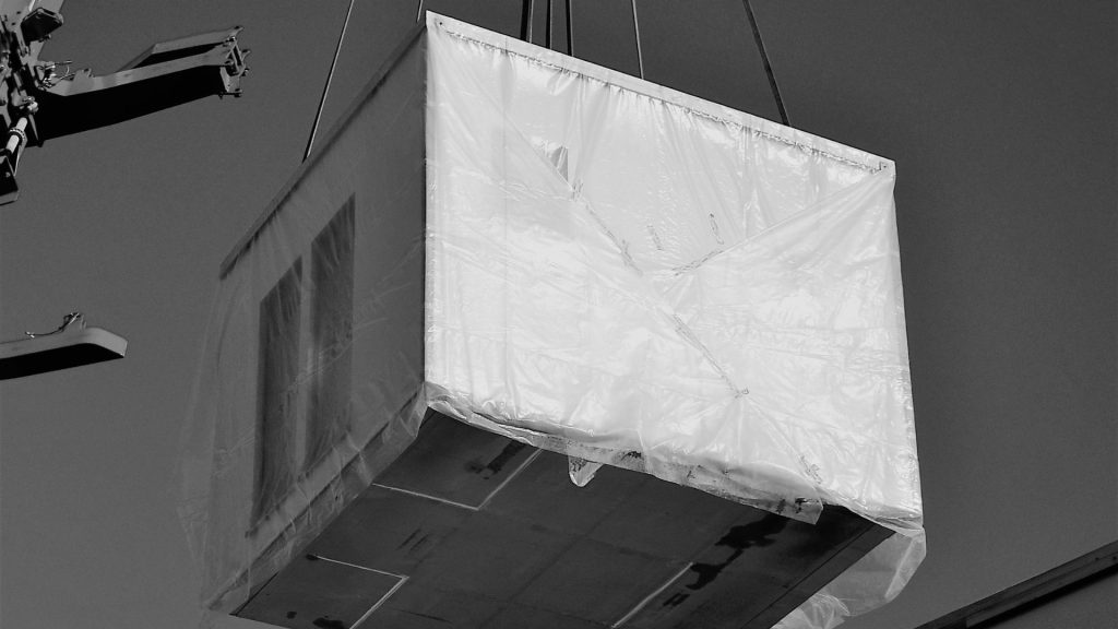 Un bloc d'habitation en béton soulevé par une grue