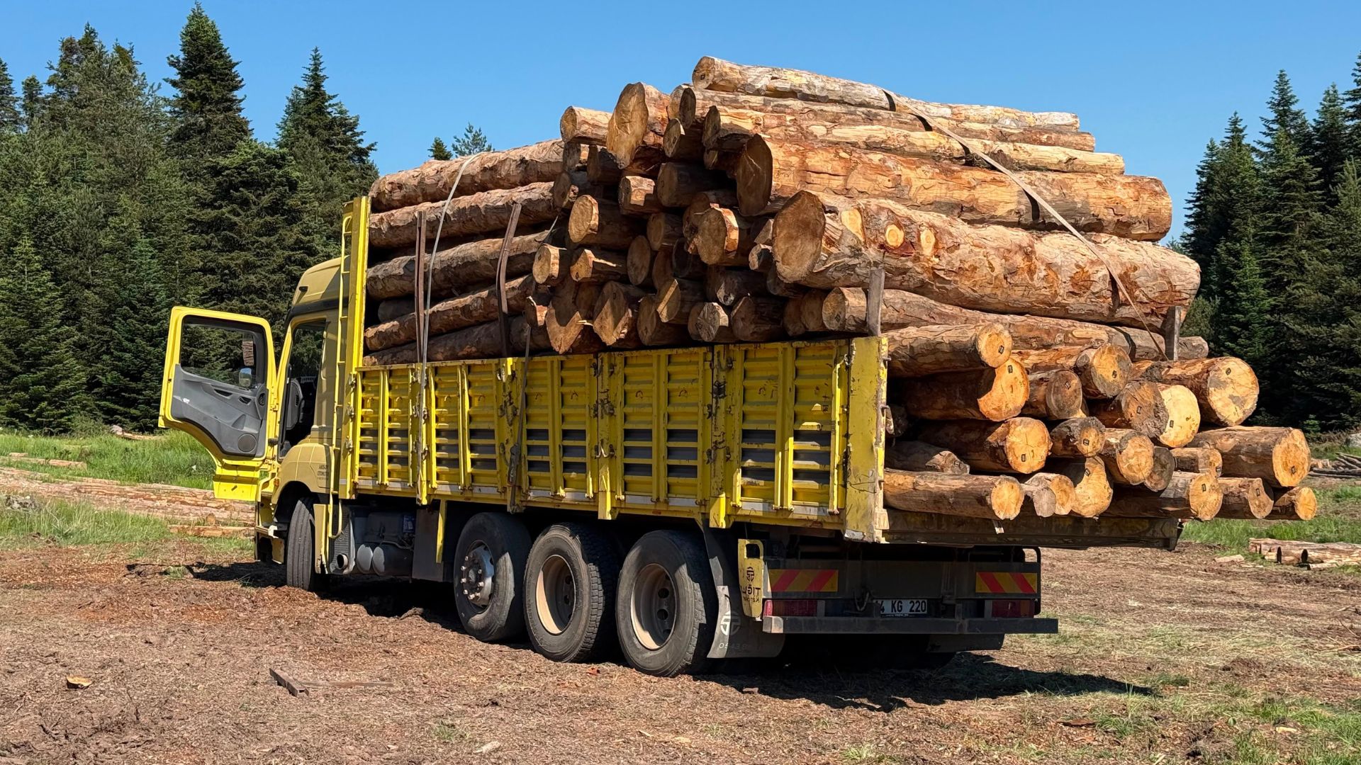 Un camion jaune transporte des grumes de bois Un camion jaune transporte des grumes de bois